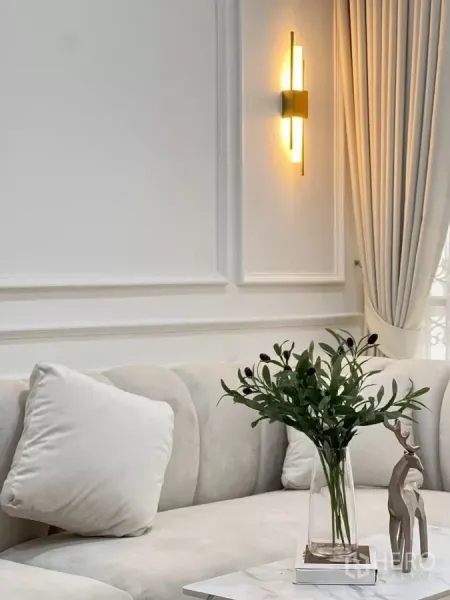 บ้าน ให้เช่าในHuai Khwang, Bangkok - ภาพระยะใกล้ผนังตกแต่งปั้นปูนและโคมไฟกิ่งสีทองเหนือโซฟากำมะหยี่สีครีม