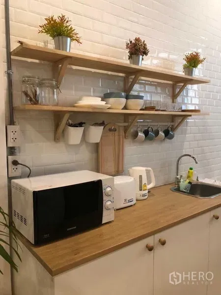 Detached House for rent in Phra Nakhon, Bangkok - Compact kitchenette with white subway tile backsplash, microwave, sink, and open wooden shelves.