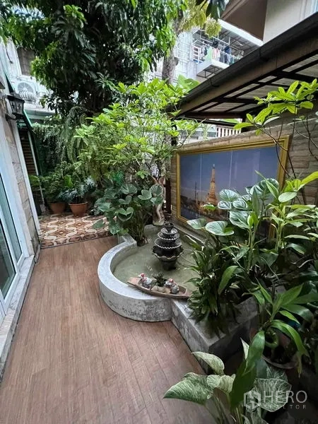 Detached House for sale in Bueng Kum, Bangkok - Side garden with a small water feature, potted plants, and lush greenery.