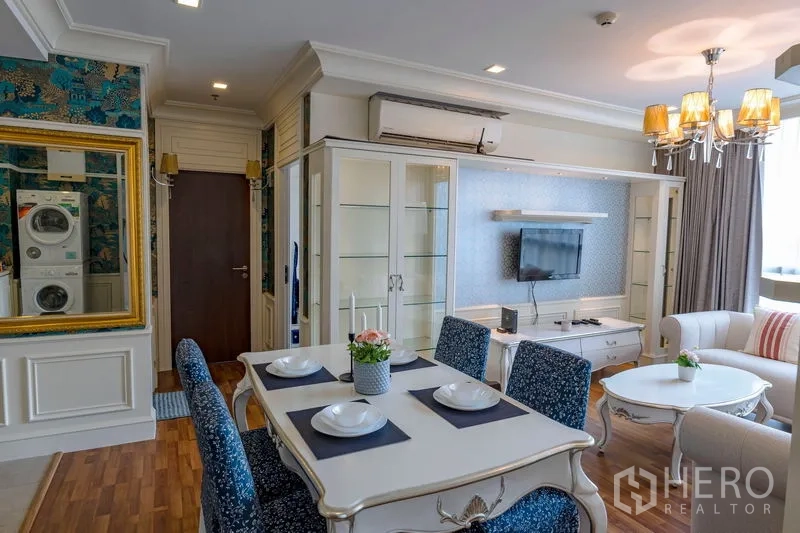 Condominium for rent in Watthana, Bangkok - Open-plan living–dining with glass display cabinet, chandelier, air conditioner and framed mirror feature wall.