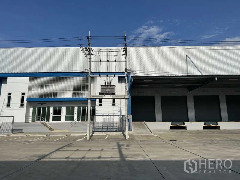工厂 出租在Bang Sao Thong, Samut Prakan - 正立面展示办公楼、变压器及多组高位装卸卷帘门