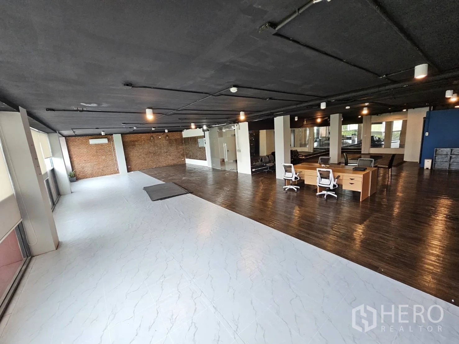 สำนักงาน ให้เช่าในWatthana, Bangkok - ออฟฟิศสว่าง มีส่วนพื้นกระเบื้องสีขาว ผนังอิฐด้านหลัง โต๊ะทำงาน และหน้าต่างยาวพร้อมมู่ลี่.