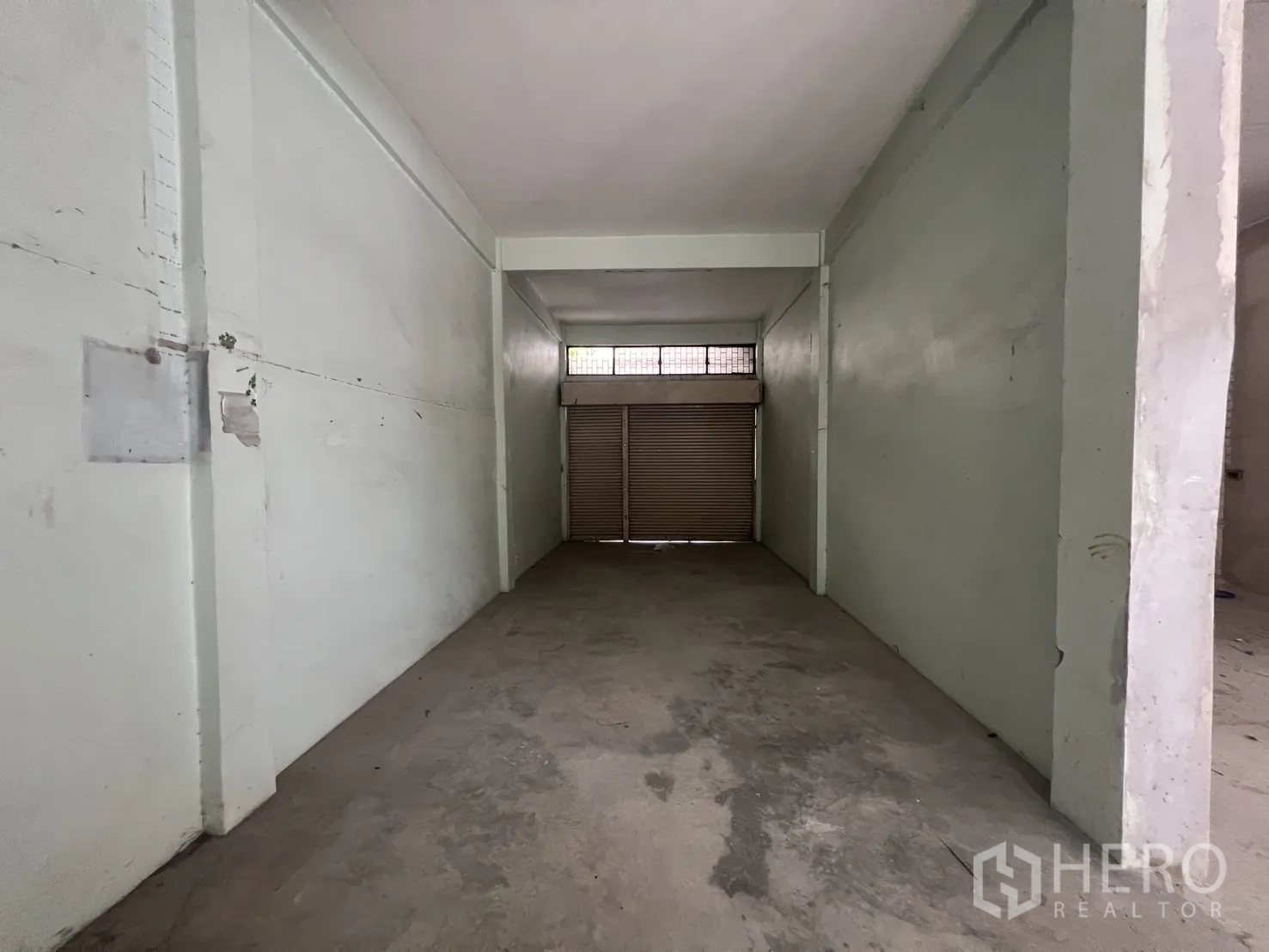 店屋 for rent in Bang Rak, Bangkok - 狭长房间，卷闸门与混凝土地面。