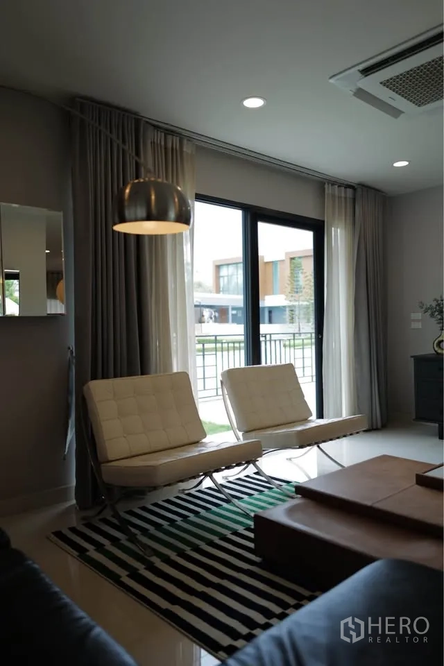 บ้านเดี่ยว for rent or sale in Bang Phli, Samut Prakan - มุมรับแขกมีเก้าอี้เลานจ์คู่ริมหน้าต่างสูงและโคมไฟตั้งพื้น