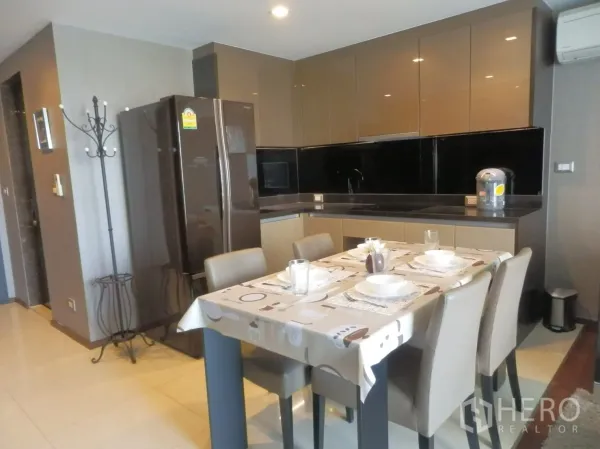 คอนโด ให้เช่าในWatthana, Bangkok - ครัวแบบเปิดตู้เคลือบเงาสีเข้ม แผงผนังสีดำ พร้อมโต๊ะทานอาหาร 4 ที่นั่ง