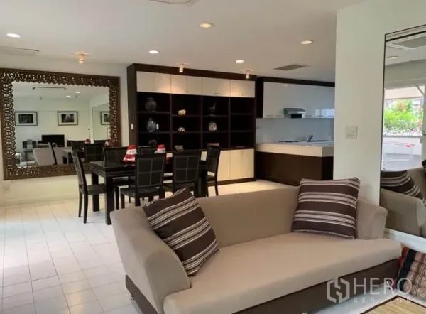 Townhouse for rent in Khlong Toei, Bangkok - Open‑plan living and dining room featuring a large decorative mirror and modern kitchenette.