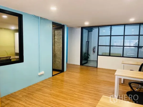 办公空间 出租在Bang Rak, Bangkok - 开放式办公室，木质地板、蓝色强调墙与黑框玻璃隔断