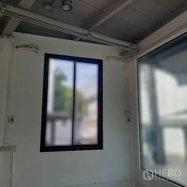 零售空间 出租在Lat Phrao, Bangkok - 店内明亮转角，配黑框窗与整面玻璃采光墙。