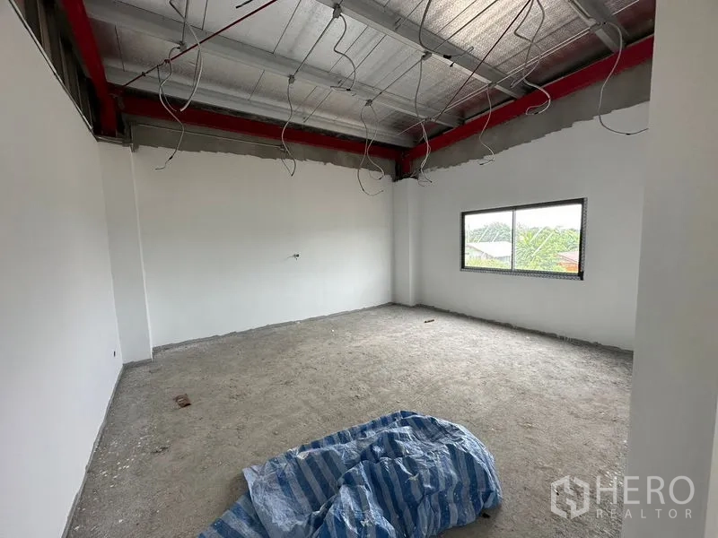Warehouse for rent or sale in Lam Luk Ka, Pathum Thani - Unfinished upstairs office room with window and ceiling insulation visible.