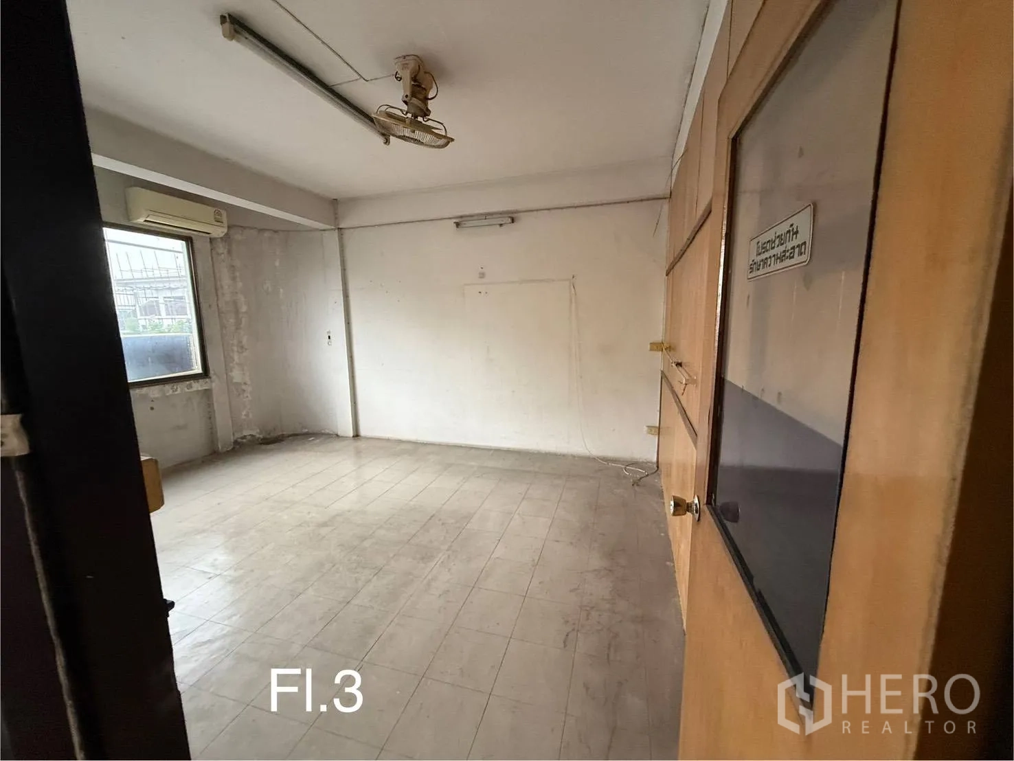 Shophouse for rent in Bang Na, Bangkok - Third-floor office room with tiled floor, wall air-conditioner and wooden door.