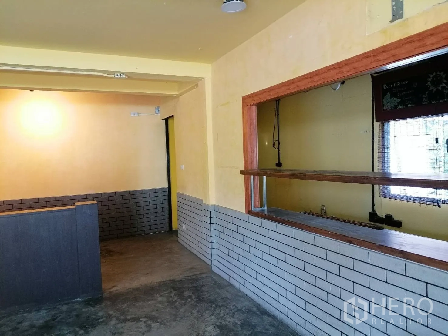 Detached House for rent in Watthana, Bangkok - Interior room with a service counter and pass-through window, brick half-wall, and concrete floor.