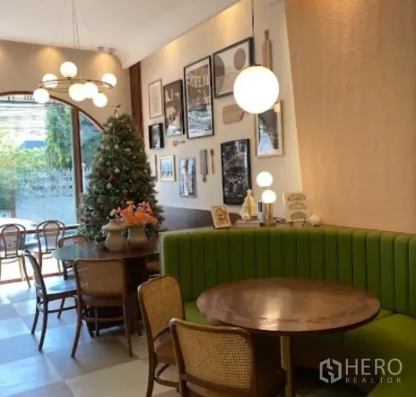 零售空间 出租在Watthana, Bangkok - 绿色卡座、圆形木桌与装饰画墙的温馨座区。