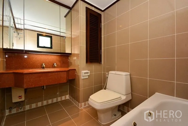 อพาร์ทเมนท์ ให้เช่าในKhlong Toei, Bangkok - ห้องน้ำที่สองพร้อมอ่างล้างหน้าคู่ กระจกบานใหญ่ อ่างอาบน้ำ และกระเบื้องโทนอบอุ่น