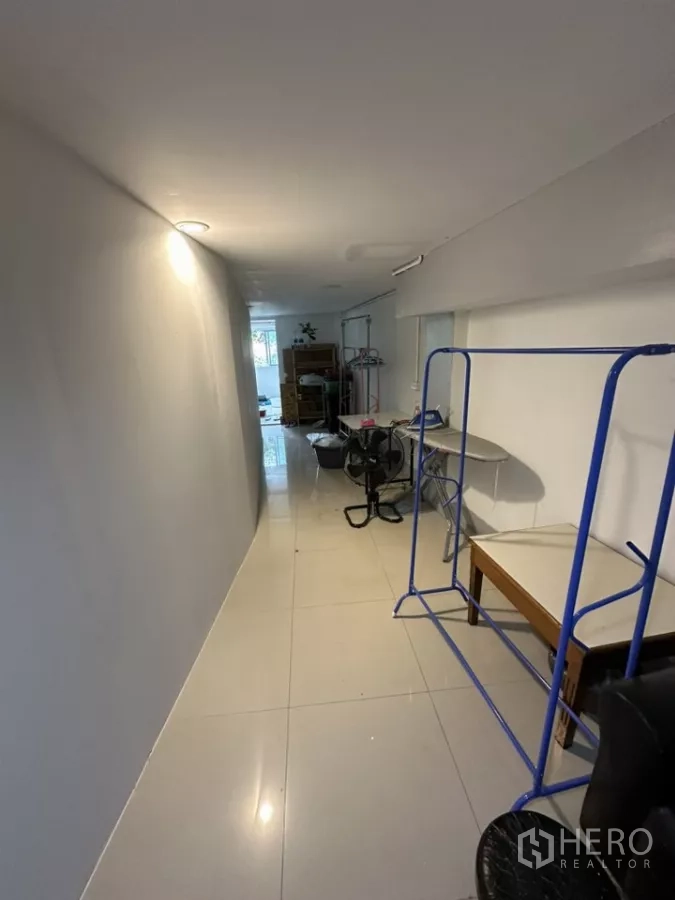 พื้นที่ขายปลีก ให้เช่า - ทางเดินยาวปูพื้นกระเบื้อง มีโครงราวสีน้ำเงินและโต๊ะ ภายในพื้นที่ค้าปลีกขนาดเล็ก