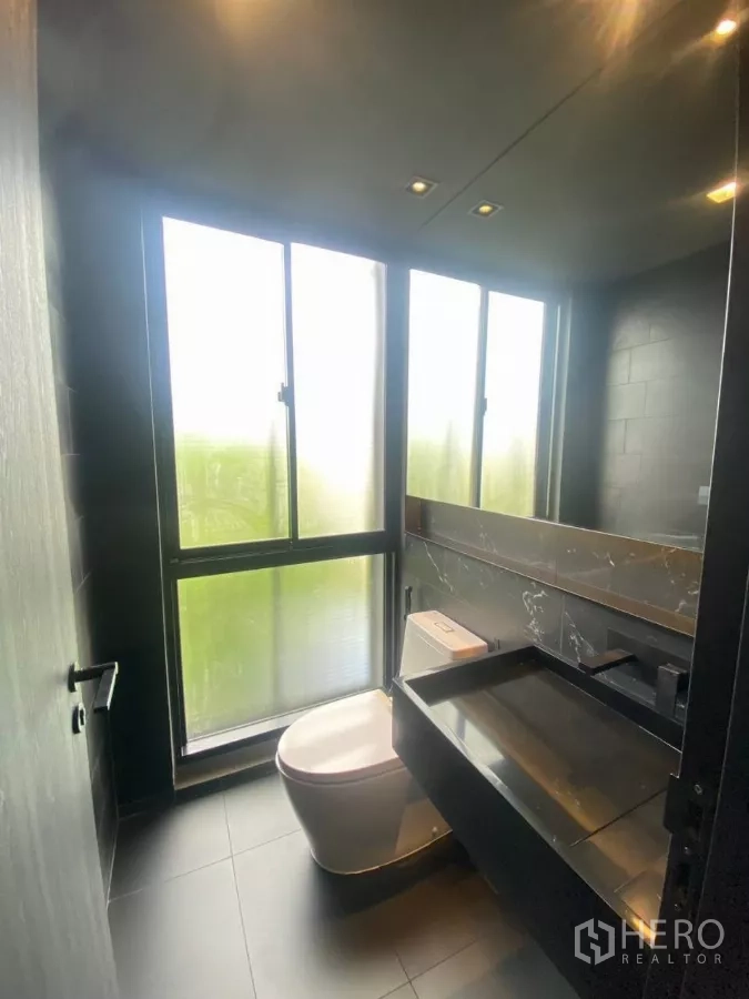 ทาวน์เฮาส์ ให้เช่าในHuai Khwang, Bangkok - ห้องน้ำเล็กมีหน้าต่างฝ้าสูงจรดพื้น เคาน์เตอร์สีดำและโถสุขภัณฑ์.