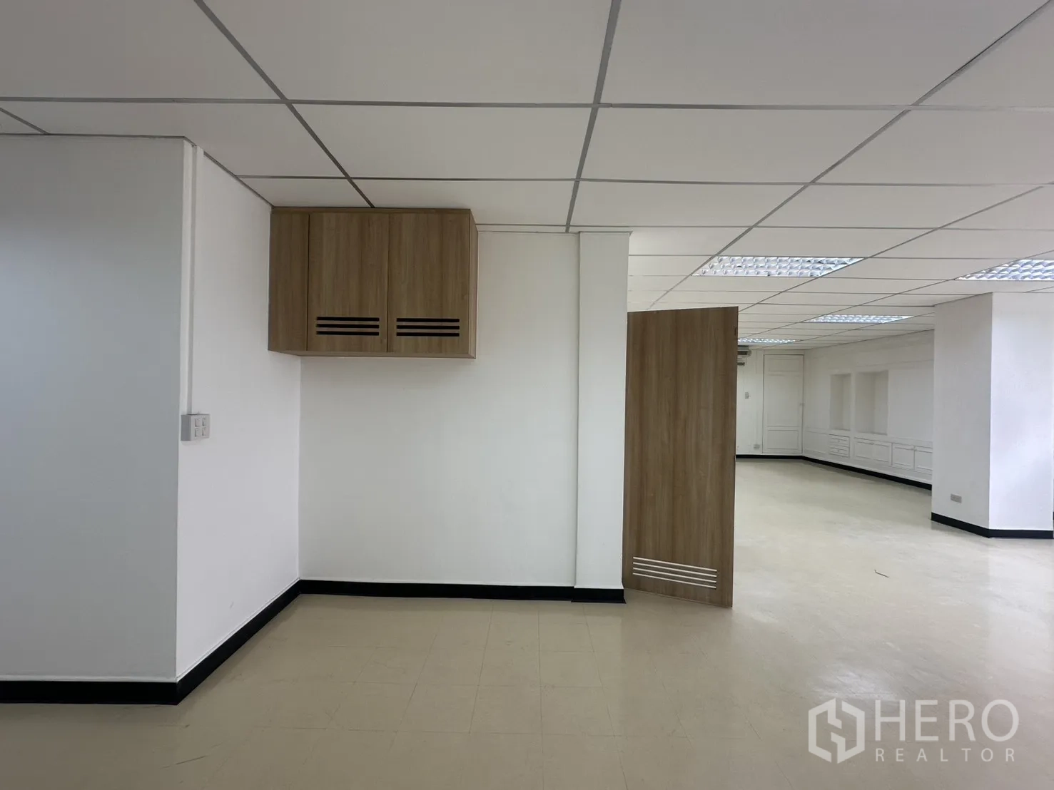 ออฟฟิศ for rent in Pathum Wan, Bangkok - มุมสำนักงานมีตู้แขวนผนังไม้ ผนังสีขาว และพื้นที่เปิดโล่งต่อเนื่องประตูไม้.
