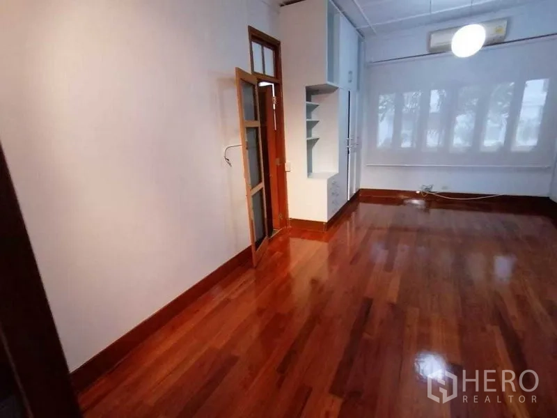 Detached House for rent in Pathum Wan, Bangkok - Long room with built-in shelving, glass door and hardwood flooring.