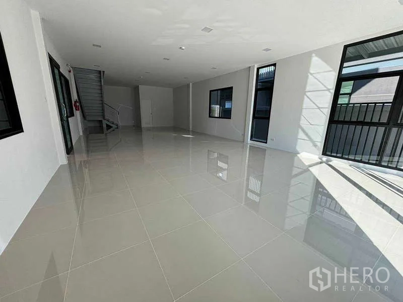 Factory for rent in Bang Bo, Samut Prakan - Ground‑floor office area with large windows, staircase access and glossy tiled floors.