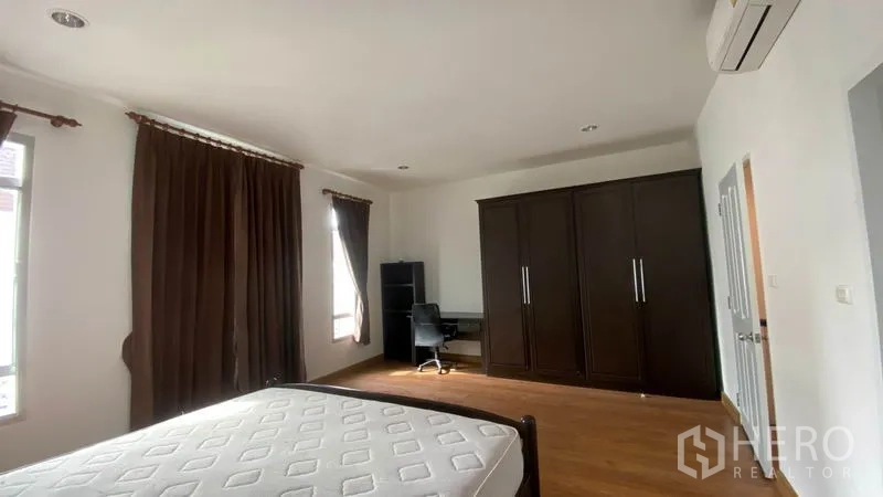 Townhouse for rent in Wang Thonglang, Bangkok - Cozy secondary bedroom with single bed, wardrobe, dresser, and wood flooring.