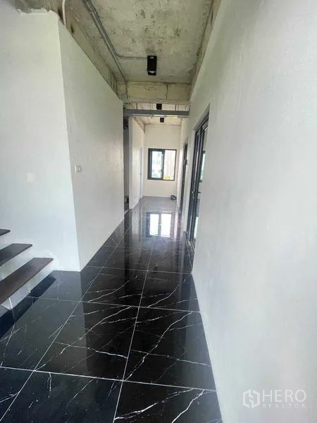 สำนักงานที่บ้าน ให้เช่าหรือขายในThanyaburi, Pathum Thani - โถงทางเดินพื้นกระเบื้องหินอ่อนสีดำเงา พร้อมบันไดและฝ้าแนวลอฟท์