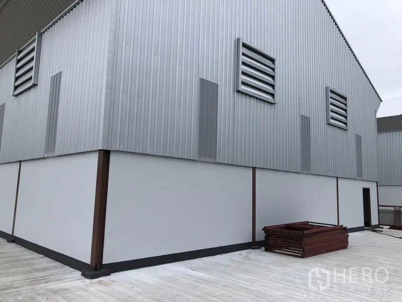 工厂 出租或出售在Sai Noi, Nonthaburi - 钢板外墙仓库侧立面，设百叶通风口与宽阔混凝土场地。