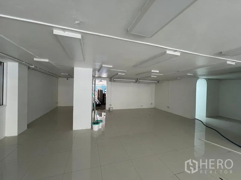 零售空间 出租在Khlong Toei, Bangkok - 开放式零售内部，白色墙面、瓷砖地面与吊顶灯。