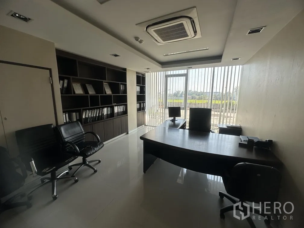 Factory for rent in Lam Luk Ka, Pathum Thani - Manager’s office with desks, extensive shelving and view through vertical blinds.