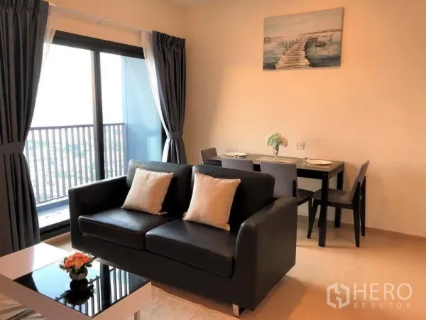 公寓 出售在Suan Luang, Bangkok - 开放式客餐厅，双人沙发、茶几与通往阳台的落地门