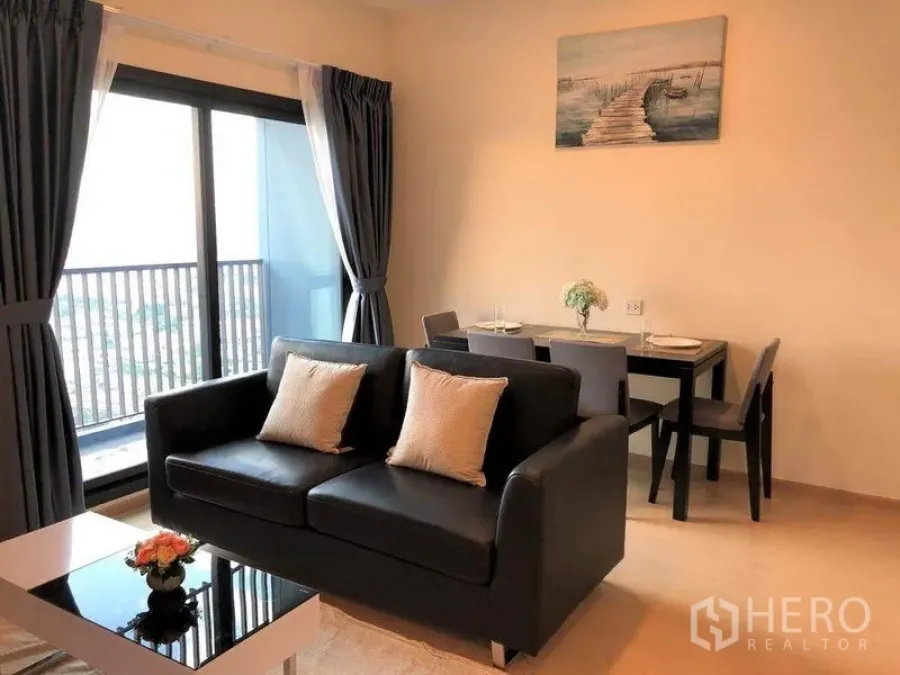 คอนโด ขายในSuan Luang, Bangkok - ห้องนั่งเล่นและรับประทานอาหารแบบเปิดโล่ง พร้อมโซฟา โต๊ะกลาง และทางออกสู่ระเบียง