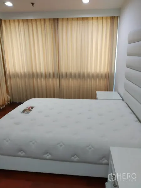 Condominium for rent in Pathum Wan, Bangkok - Master bedroom with padded headboard, king bed, floor-to-ceiling curtains and warm wood flooring.