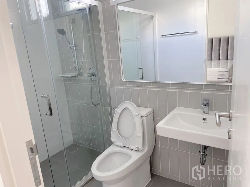 联排别墅 出租在Prawet, Bangkok - 现代浴室，玻璃淋浴间、坐便器与壁挂洗手盆。