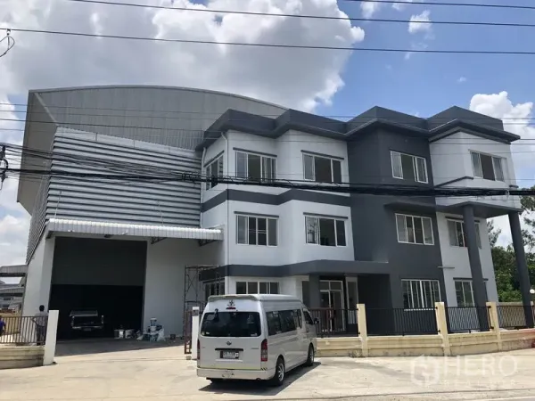 货栈 出租或出售在Lam Luk Ka, Pathum Thani - 正立面展示办公楼与仓库相连，设大型卷帘门入口。