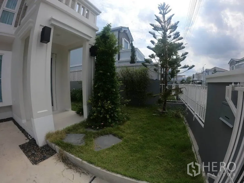 Detached House for rent in Prawet, Bangkok - Front garden with lawn, shrubs, pathway stones and covered porch by the gate.