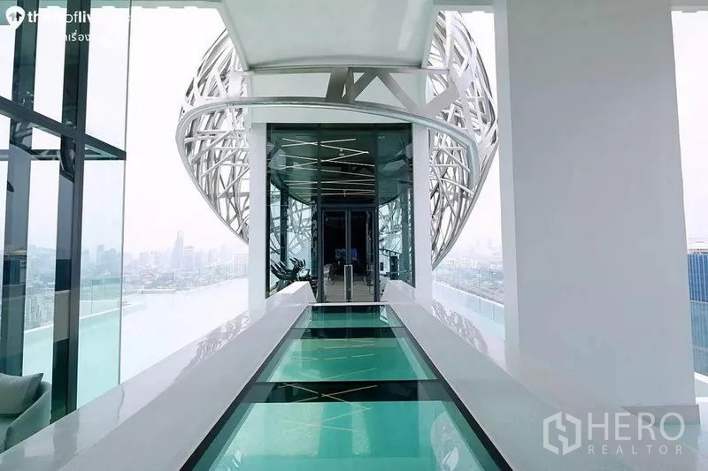 公寓 出租在Watthana, Bangkok - 穿越泳池的玻璃空中走廊，通往健身房，远眺天际线。