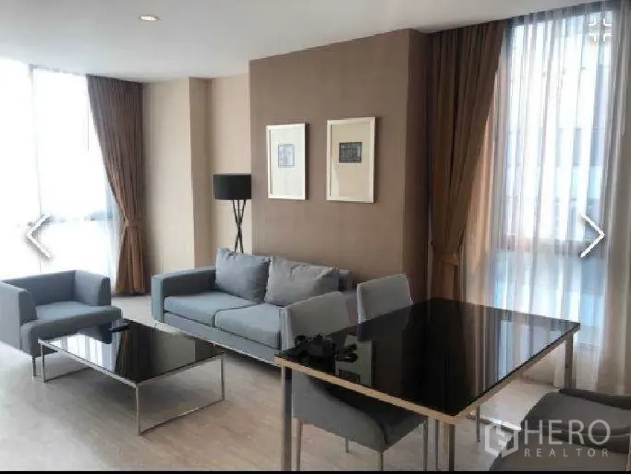 公寓 出租在Watthana, Bangkok - 开放式客餐厅，灰色沙发、黑色餐桌与转角窗