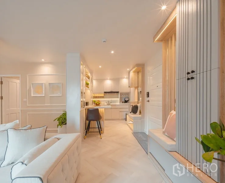 Condominium for sale in Yan Nawa, Bangkok - View from lounge to entry and kitchen with island and seating in neutral tones.