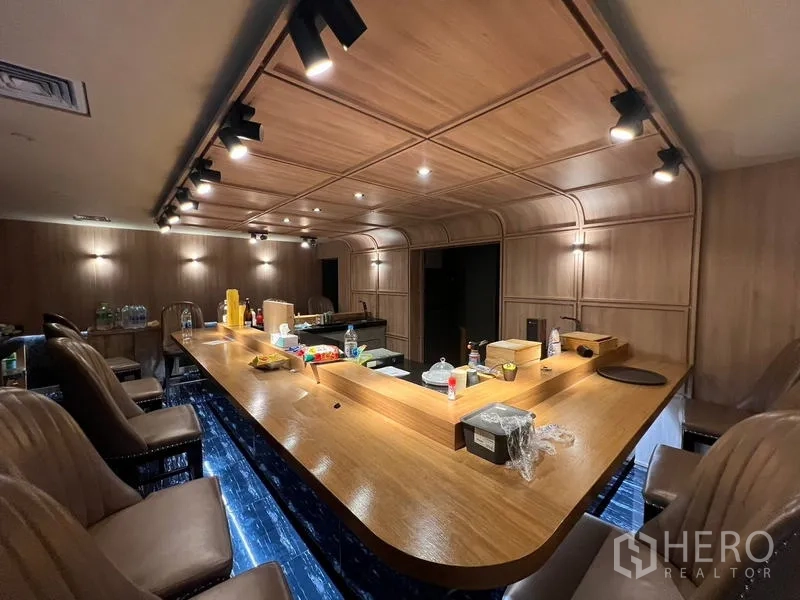 พื้นที่ขายปลีก ให้เช่าในBang Rak, Bangkok - เคาน์เตอร์บาร์ไม้พร้อมไฟสปอตไลต์และเก้าอี้บาร์บุผ้านุ่ม.