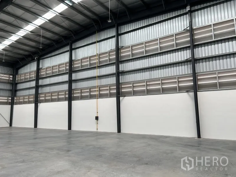 Factory for rent in Bang Sao Thong, Samut Prakan - Factory wall with louvered ventilation panels and black steel columns.