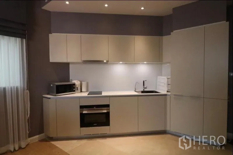 คอนโด ให้เช่าในKhlong San, Bangkok - ครัวรูปตัวแอลสไตล์โมเดิร์น ตู้สีขาว เตาอบ เตาไฟฟ้า ไมโครเวฟ และไฟใต้ตู้