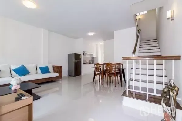 Townhouse for rent in Watthana, Bangkok - Spacious lounge with sofa, dining set and stairway leading to upper floors.