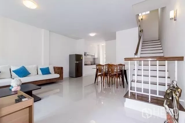 Townhouse for rent in Watthana, Bangkok - Spacious lounge with sofa, dining set and stairway leading to upper floors.