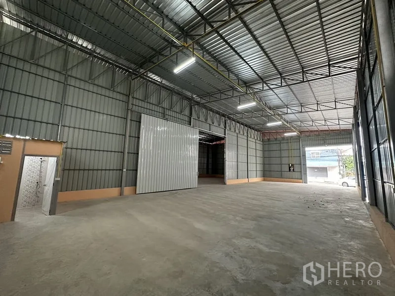 货栈 出租在Bueng Kum, Bangkok - 明亮的仓库空间，正面大型卷门，面向街道的装卸区域。