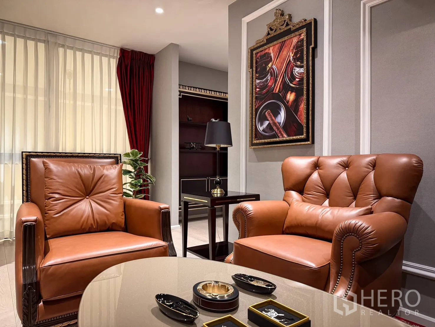 Detached House for rent or sale in Lak Si, Bangkok - Sitting corner with two leather armchairs, artwork, and sheer curtains.