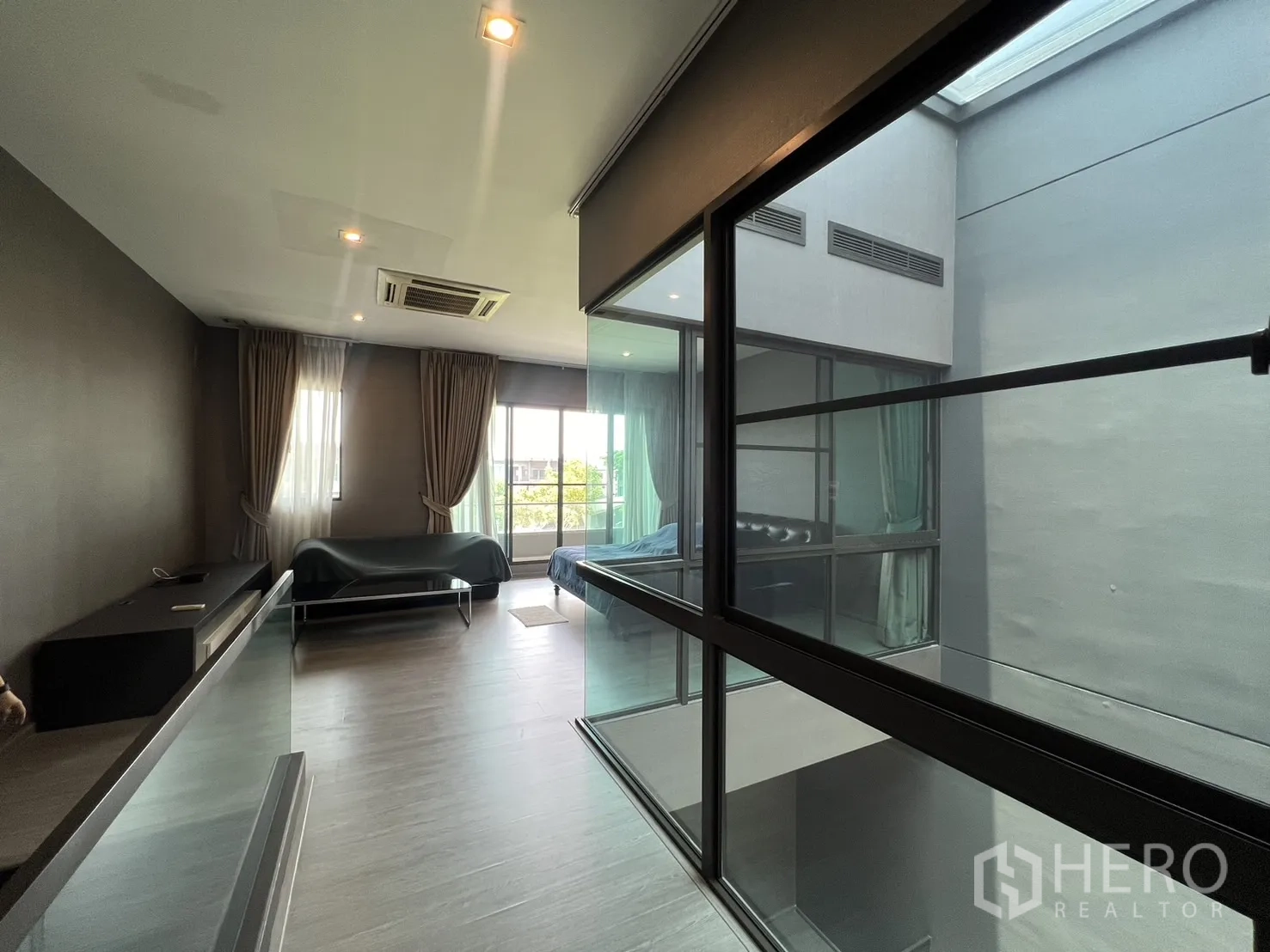 联排别墅 出租在Lat Phrao, Bangkok - 樓上多功能起居或臥室，連通陽台與中庭玻璃牆。