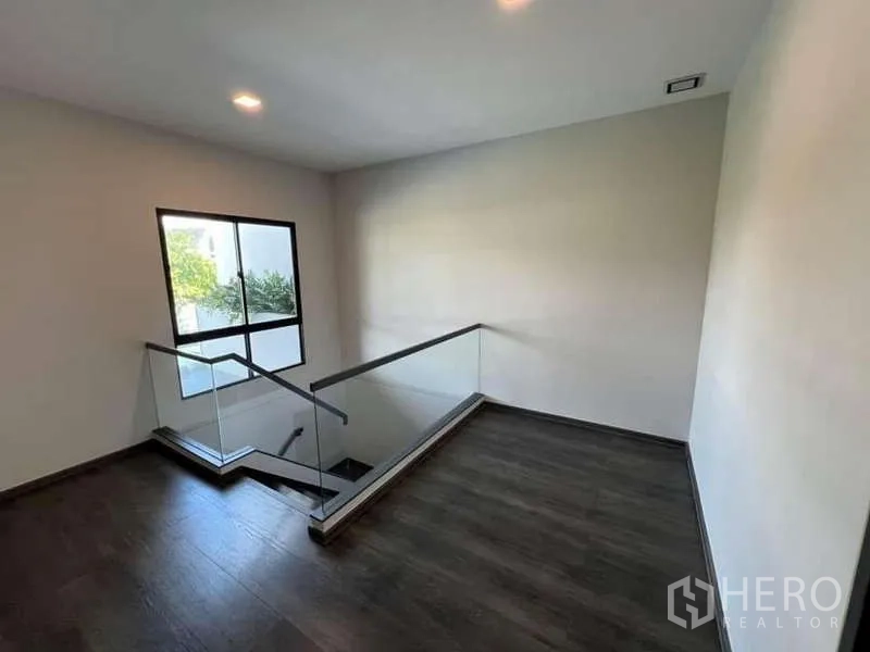 Detached House for rent or sale in Bang Phli, Samut Prakan - Upper landing with glass balustrade and window bringing natural light to the staircase.