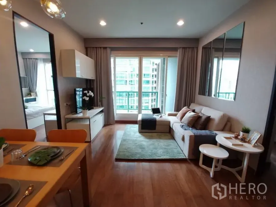 คอนโด ให้เช่าในPathum Wan, Bangkok - ห้องนั่งเล่นสว่าง โซฟา พื้นไม้ ประตูระเบียงกระจกสูง มองวิวเมือง