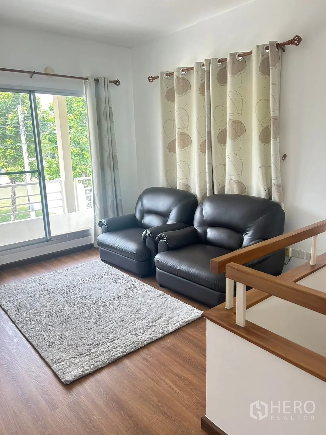 独栋房屋 for rent in Bang Na, Bangkok - 二楼起居区配两张皮沙发、地毯与阳台推拉门。