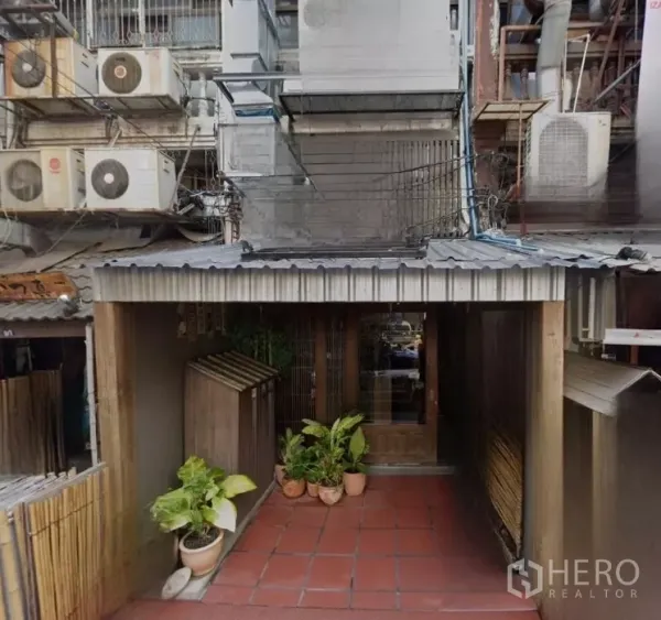 店屋 出租在Bang Rak, Bangkok - Bang Rak商铺外立面，金属雨棚、红砖地面与绿植入口。