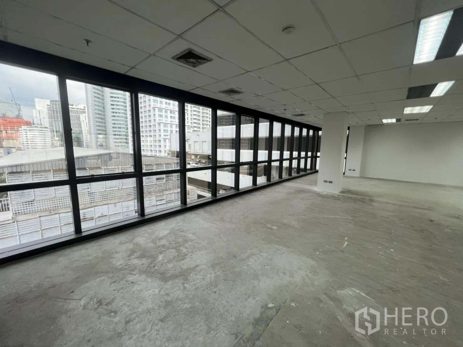 สำนักงาน ให้เช่าในWatthana, Bangkok - ผนังกระจกยาวกรอบสีดำ มองเห็นตึกใกล้เคียง พื้นคอนกรีตพร้อมตกแต่ง