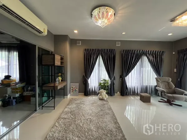 บ้าน ให้เช่าหรือขายในLat Krabang, Bangkok - มุมนั่งเล่นมีโคมไฟระย้า เครื่องปรับอากาศ และหน้าต่างสูงพร้อมผ้าม่าน